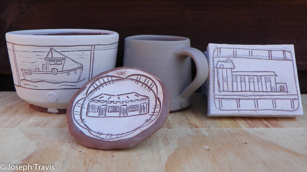 boats and buildings carved on pots that are covered in white clay with red clay showing through the drawings.